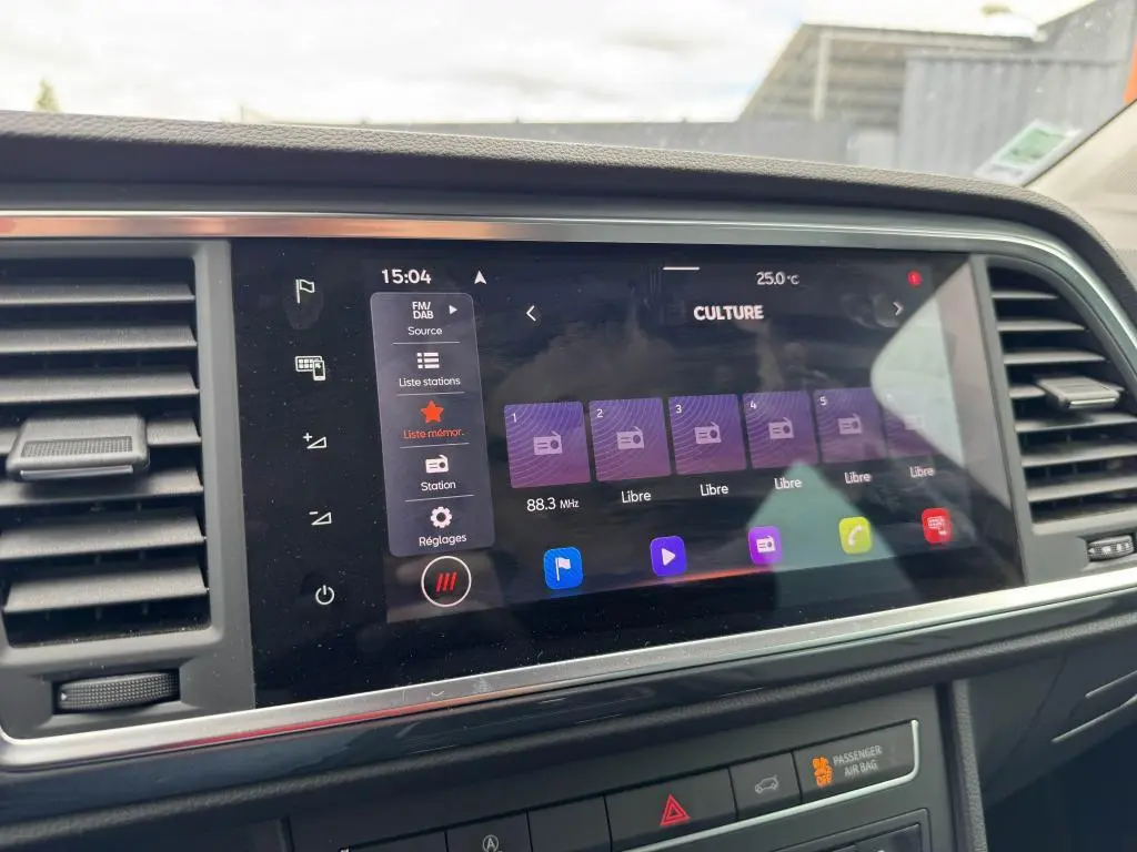 Écran tactile central du tableau de bord du SEAT Ateca 2023 noir, affichant la radio FM/DAB et les réglages multimédia.