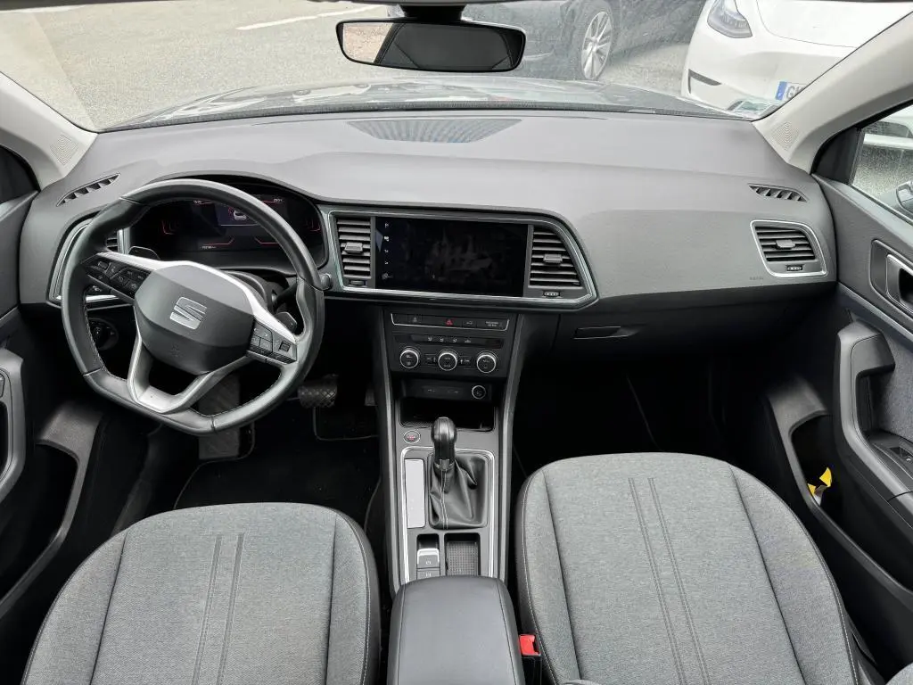 Vue intérieure avant du SEAT Ateca 2023 noir, montrant le tableau de bord, volant multifonction et sièges en textile gris.