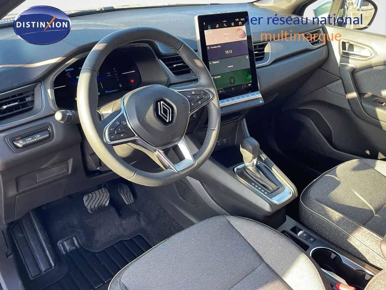 Vue intérieure côté conducteur du Renault Captur E-Tech Hybrid 2025, avec volant multifonction et écran tactile vertical.