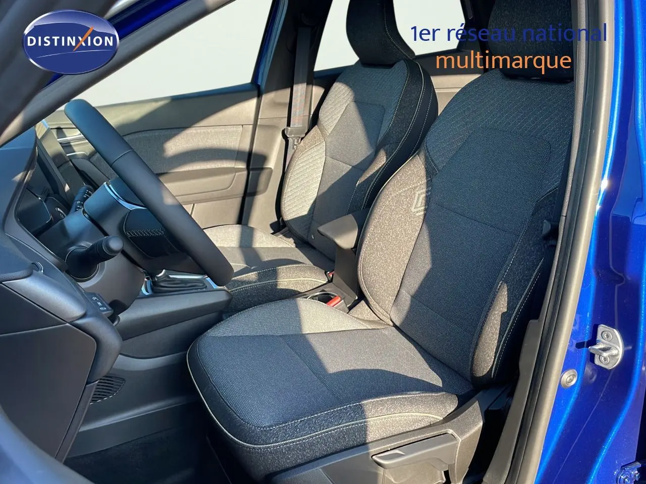 Vue intérieure côté gauche du Renault Captur bleu Iron Metal avec sièges tissu gris et volant visible.