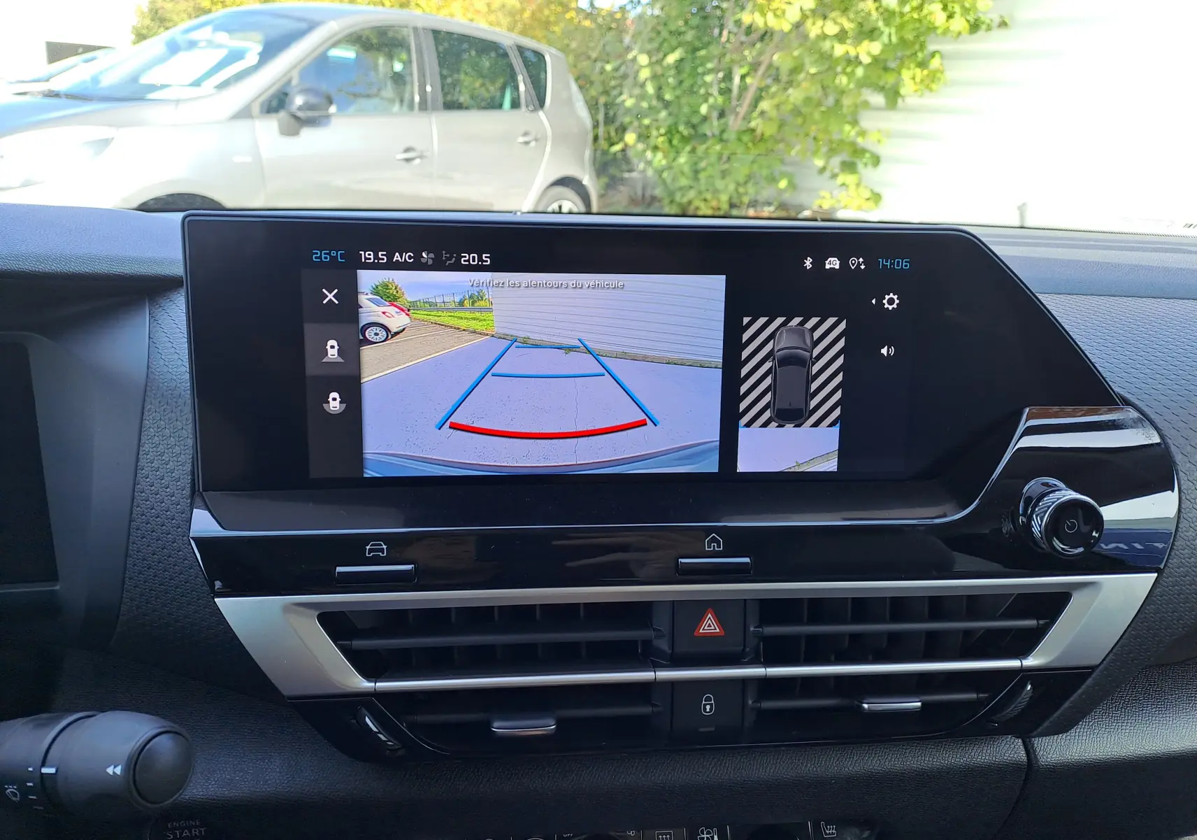 Écran central du tableau de bord d'une Citroën C4 hybride 2025 montrant la caméra de recul et les capteurs de stationnement.