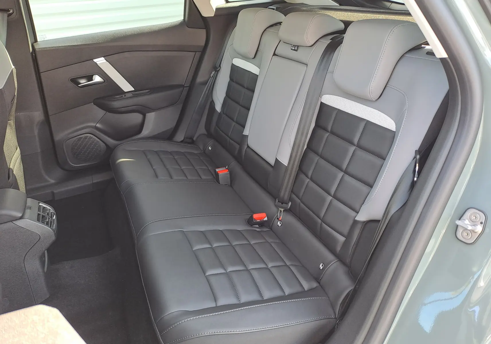 Vue intérieure côté droit des sièges arrière en cuir noir et gris de la Citroën C4 hybride 2025 Manhattan Green.