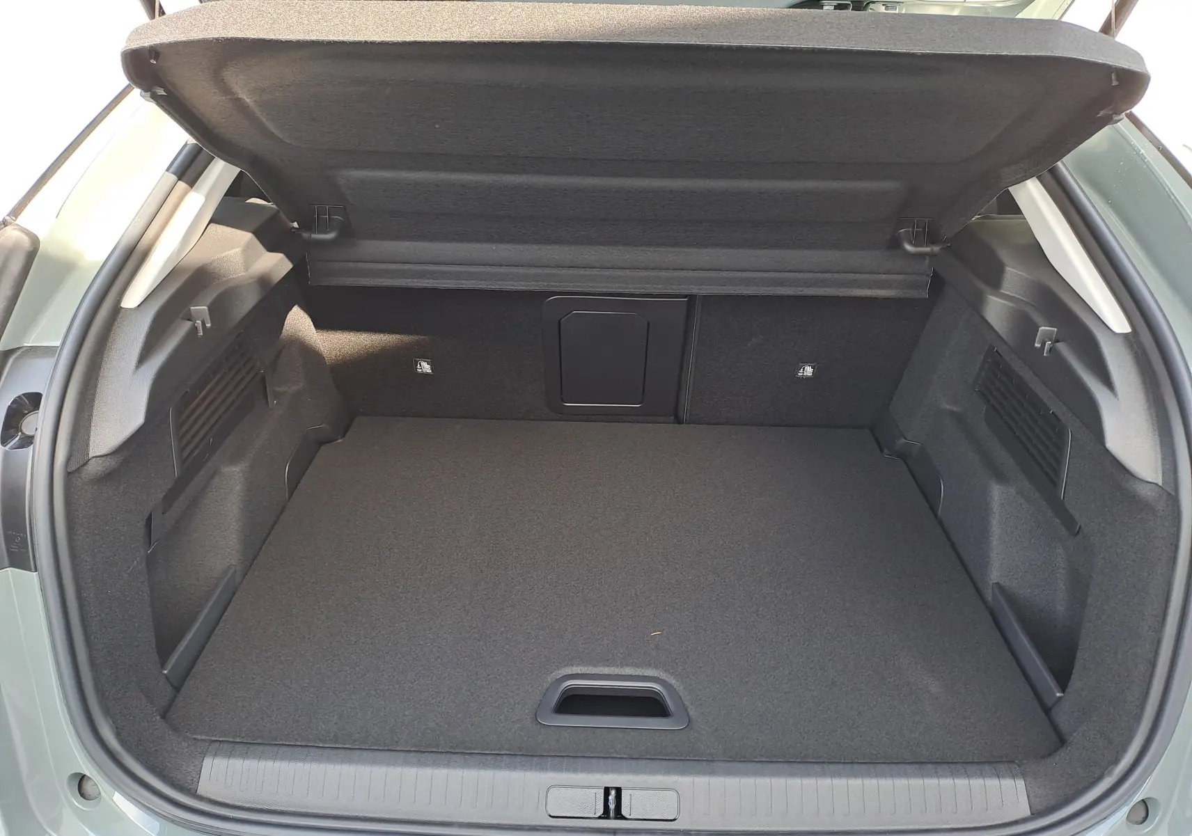 Coffre ouvert vu de l'arrière d'une Citroën C4 hybride 2025 Manhattan Green, espace de chargement vide et bien agencé.