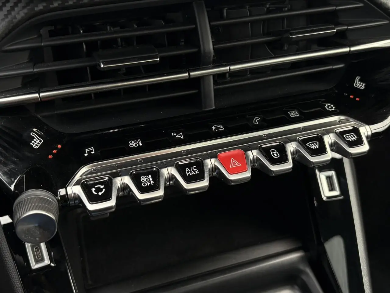 Gros plan sur la console centrale noire brillante de la Peugeot 208 GT avec ses boutons métalliques et touches tactiles rétroéclairées