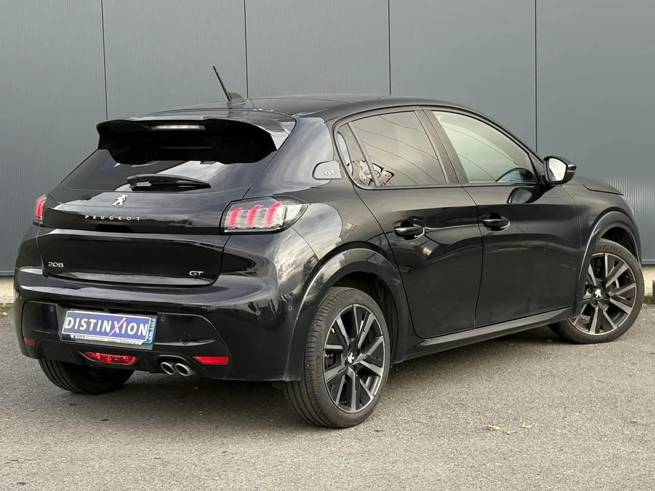 Peugeot 208 GT noire vue en 3/4 arrière droit avec double sortie d’échappement chromée et jantes alliage 17 pouces.