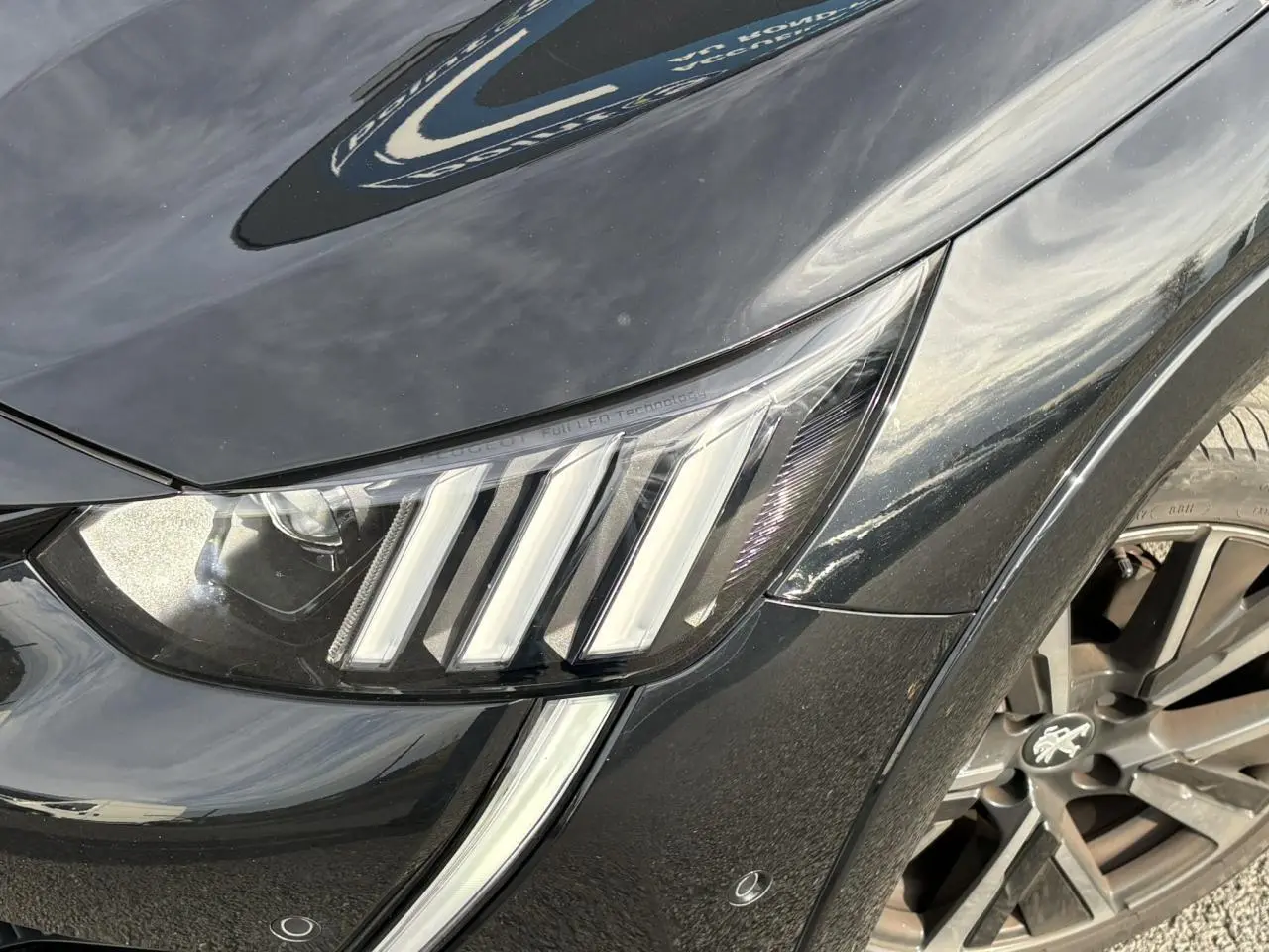 Gros plan sur le phare avant gauche et la jante alliage 17'' noir perla de la Peugeot 208 GT 2023.