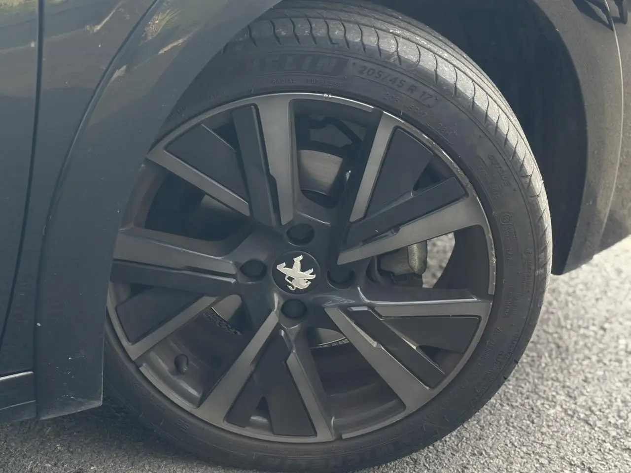 Gros plan sur la roue avant gauche noire avec jante alliage 17'' du Peugeot 208 GT noir perla.