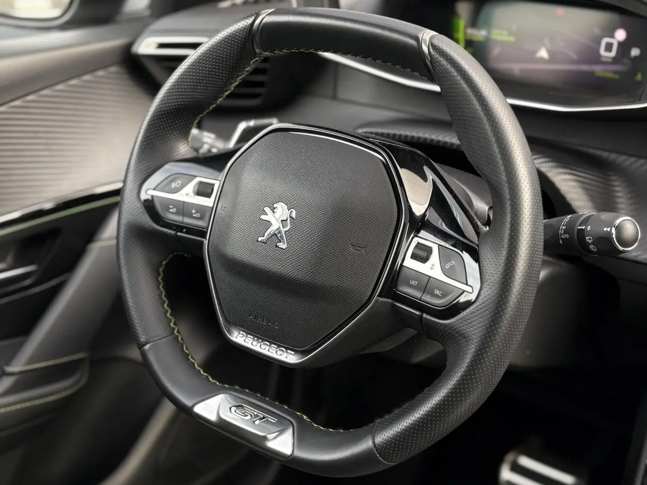 Volant cuir noir avec surpiqûres vertes et badge GT de la Peugeot 208 1.2 PureTech 130 vue de face intérieure.