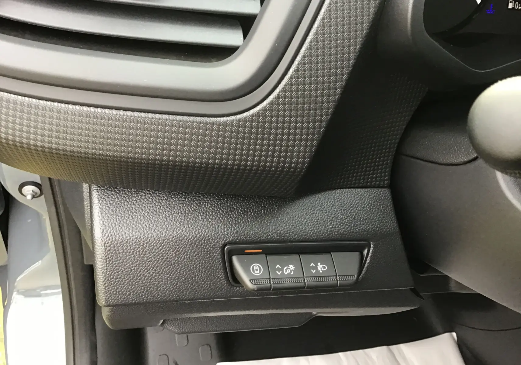 Détail intérieur du tableau de bord côté gauche du Renault Trafic Fourgon gris urbain, avec commandes d’éclairage et verrouillage.