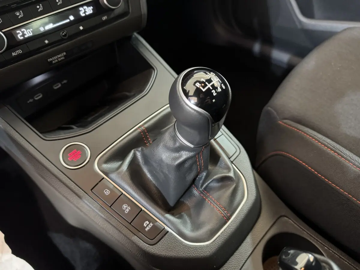 Gros plan sur le levier de vitesses manuel noir avec surpiqûres rouges dans l'habitacle de la SEAT Ibiza rouge 2024.