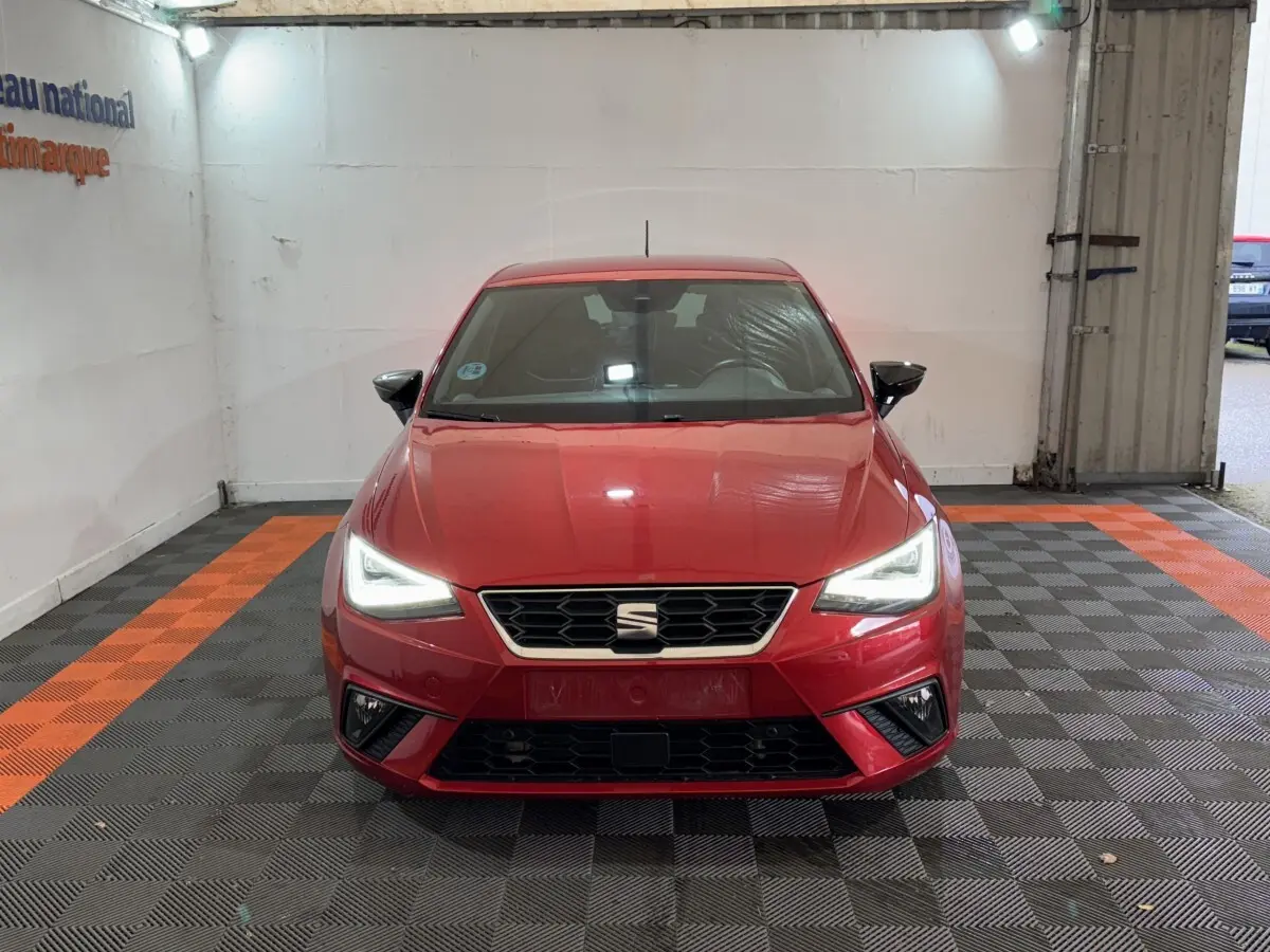 Vue de face d'une SEAT IBIZA 1.0 TSI 110 FR rouge avec phares LED allumés dans un garage.