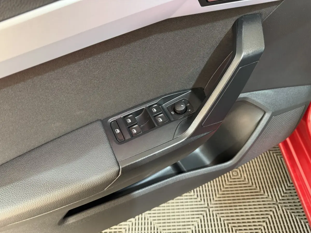 Détail de la porte côté conducteur de la SEAT IBIZA rouge 2024 avec commandes des vitres et rétroviseurs électriques.