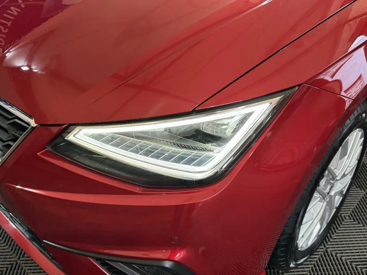 Gros plan sur le phare avant droit LED d'une SEAT IBIZA 1.0 TSI 110 FR rouge 2024, avec jante alu visible.