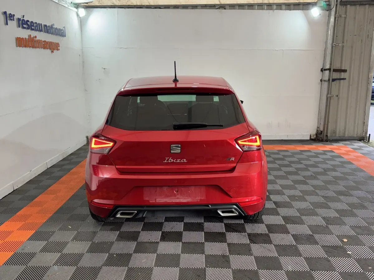 Vue arrière d'une SEAT Ibiza 1.0 TSI 110 FR rouge avec feux LED triangulaires et double sortie d'échappement rectangulaire.