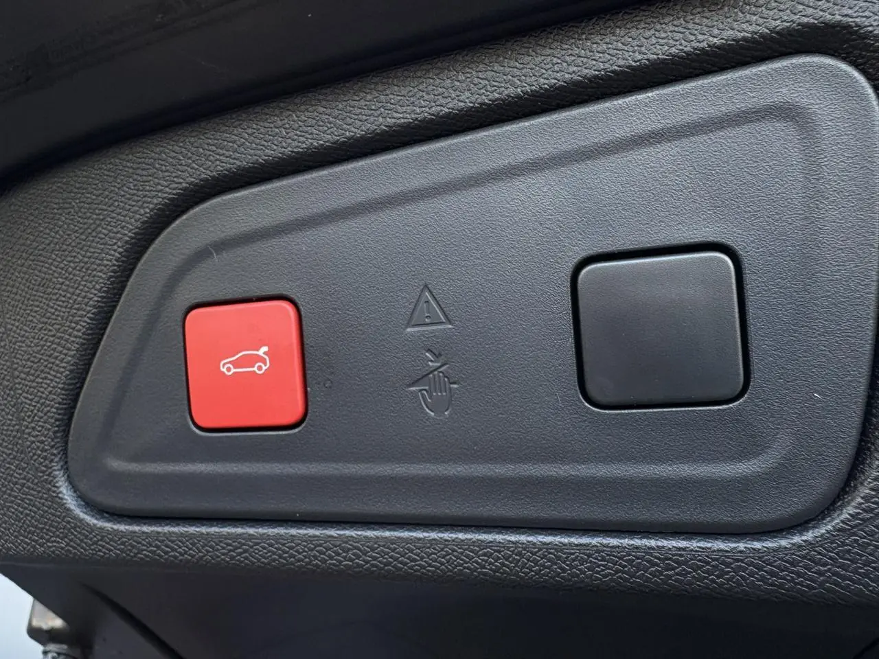 Gros plan sur le bouton rouge d'ouverture électrique du hayon du Citroën C5 Aircross blanc, version 2025.