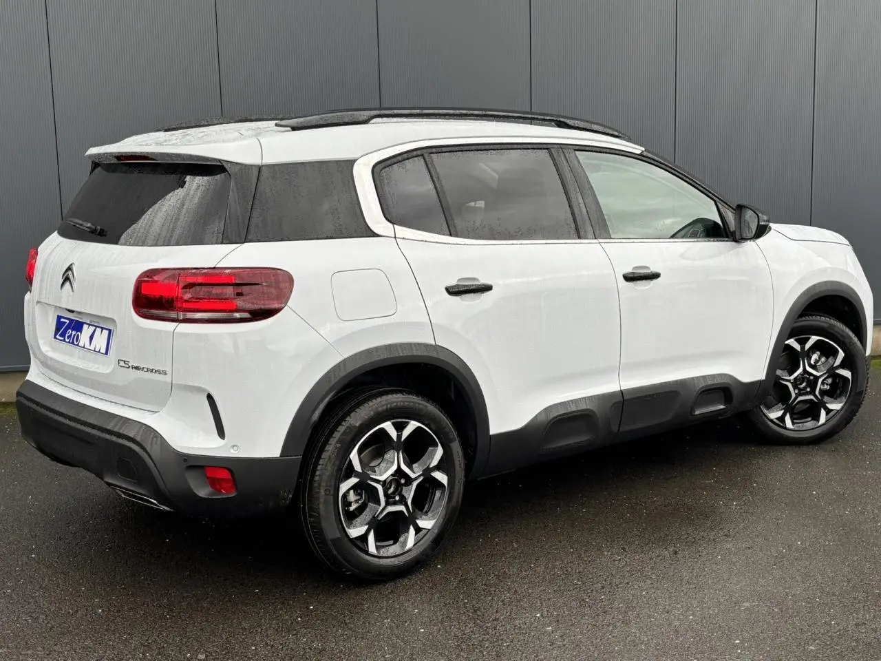 Vue 3/4 arrière droite du Citroën C5 Aircross blanc Okénite avec toit noir et protections latérales noires.