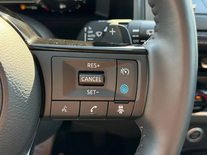 Gros plan sur les commandes au volant cuir du Nissan Qashqai noir Kuro, avec régulateur de vitesse et assistance active.