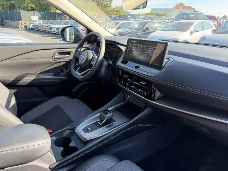 Intérieur du Nissan Qashqai 2025 vu côté conducteur, tableau de bord noir avec écran tactile et volant cuir multifonction.
