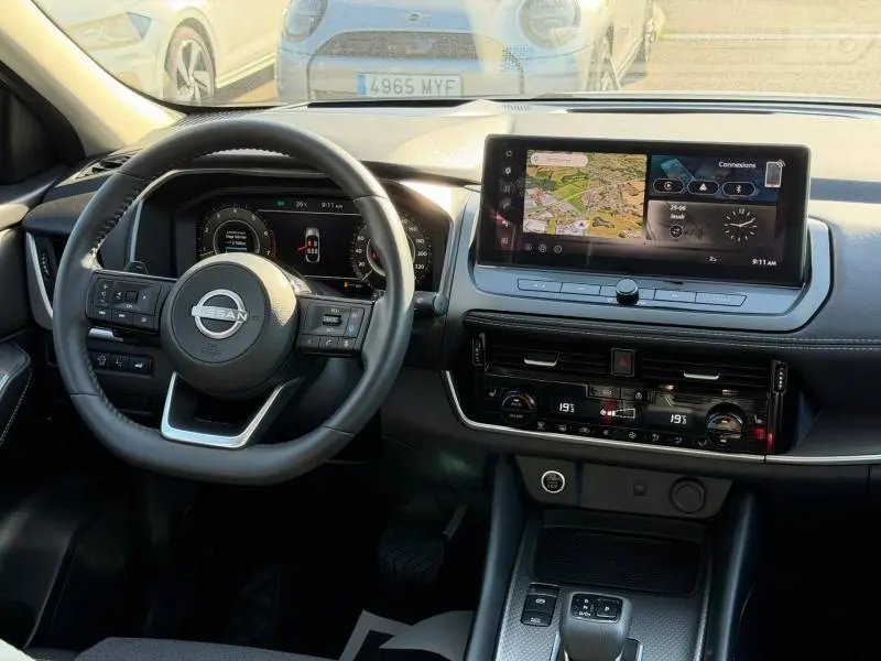 Vue intérieure du tableau de bord du Nissan Qashqai 2025 avec volant cuir multifonction et écran tactile central.