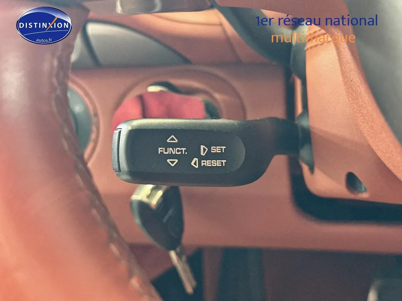 Gros plan sur la commande de régulateur de vitesse dans l'habitacle cuir marron d'une Porsche 911 gris 2009.