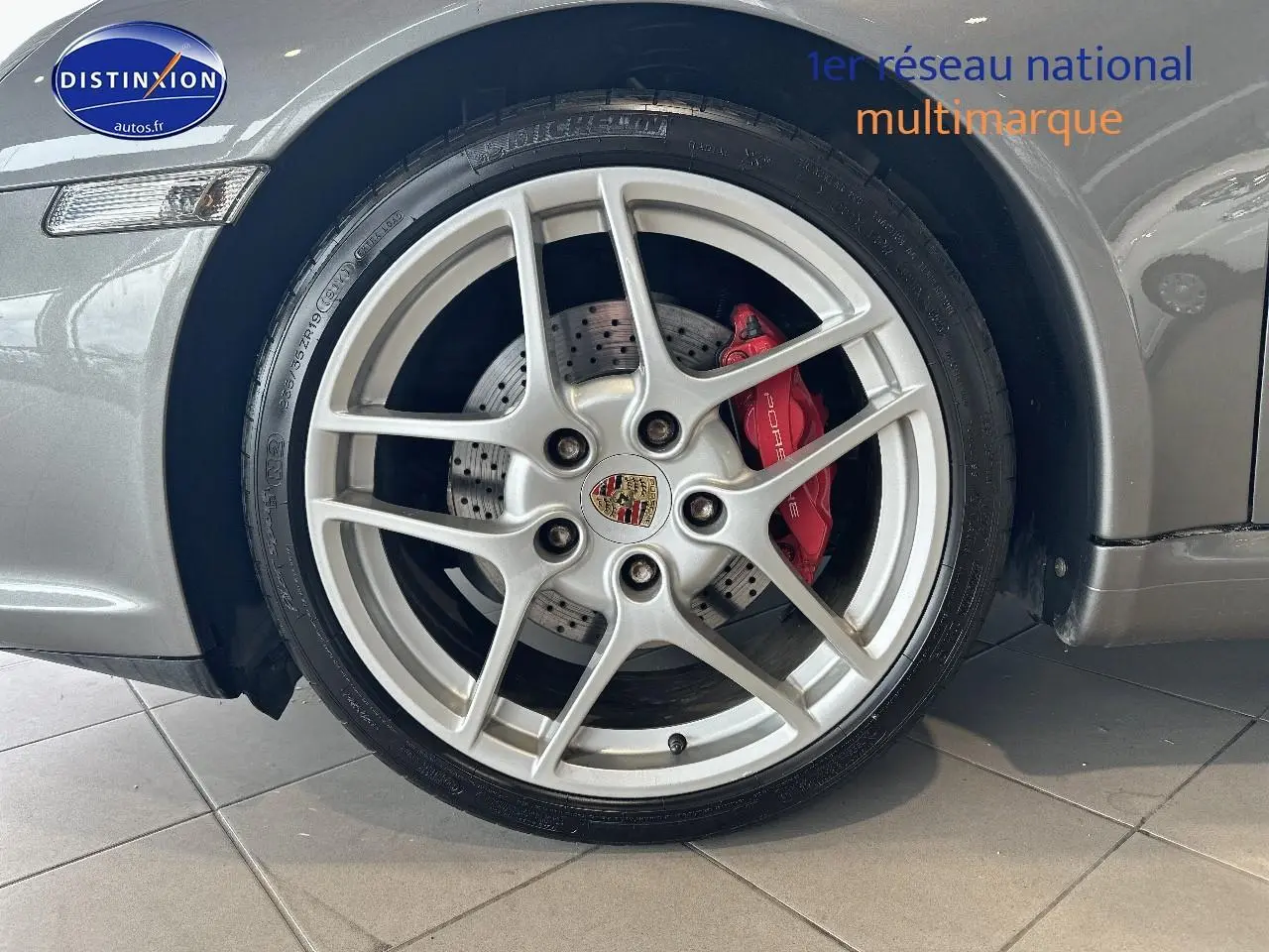 Gros plan sur la jante alu argentée avec étrier de frein rouge d'une Porsche 911 (997) carrera pdk gris côté avant droit.