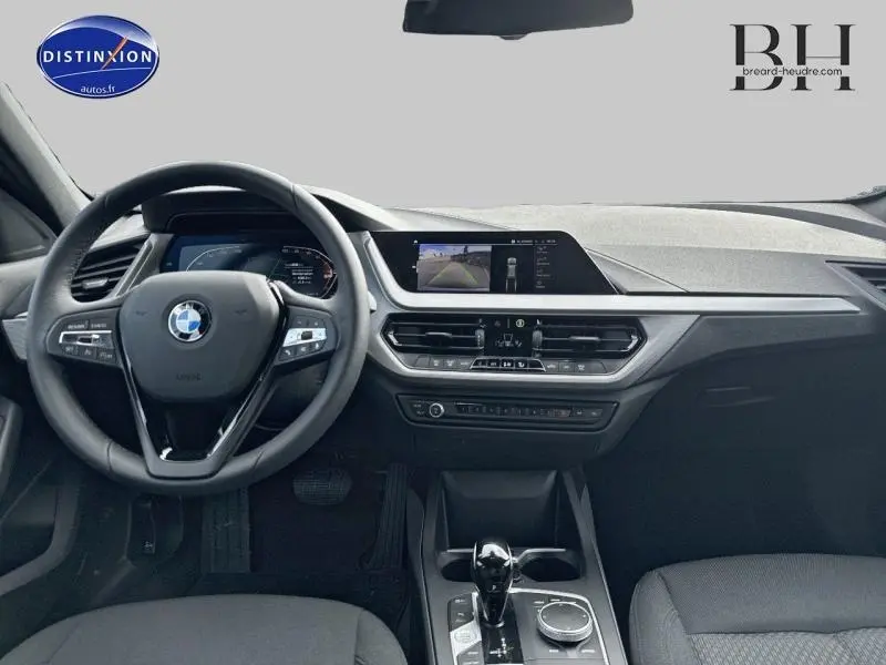 Tableau de bord et volant cuir multifonction de la BMW Série 1 116dA 2022, avec écran tactile et caméra de recul affichée.