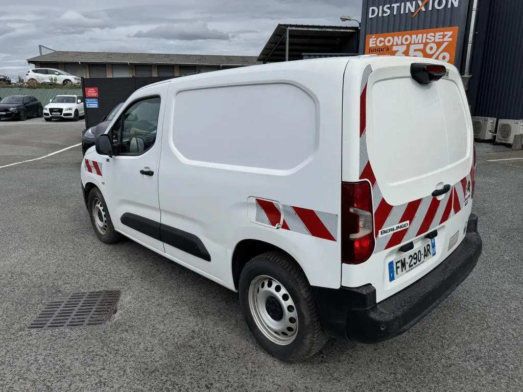Vue 3/4 arrière droite d’un utilitaire Citroën Berlingo blanc avec bandes réfléchissantes rouges et blanches sur portes arrière.