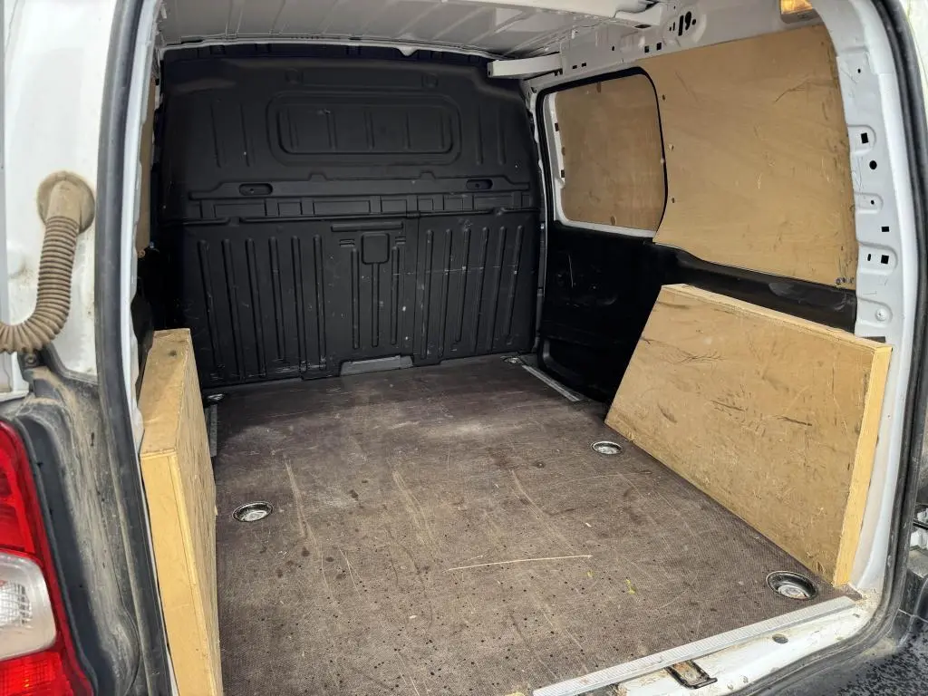 Vue intérieure arrière du Citroën Berlingo blanc 2019, montrant l'espace de chargement avec panneaux en bois et anneaux d'arrimage.