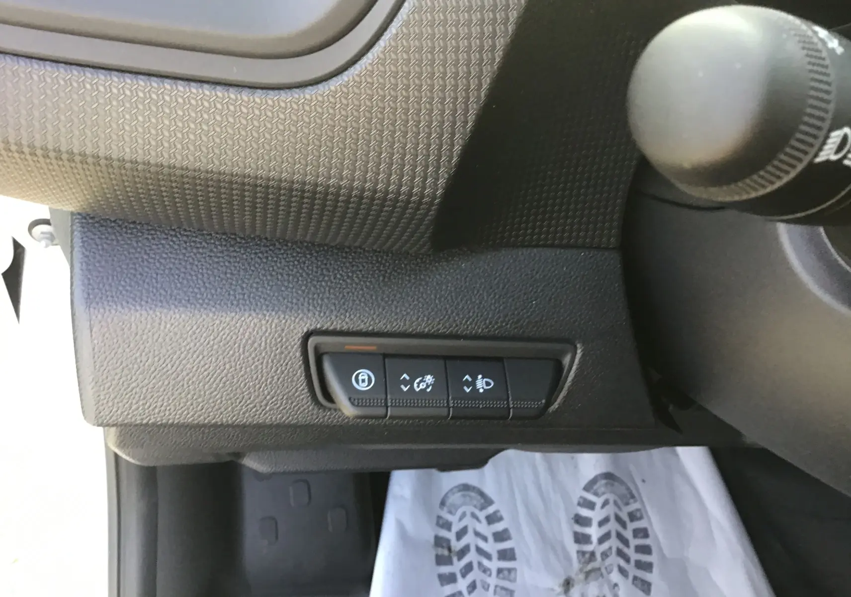 Gros plan sur les commandes de réglage d’éclairage et verrouillage côté gauche du tableau de bord du Renault Trafic blanc.