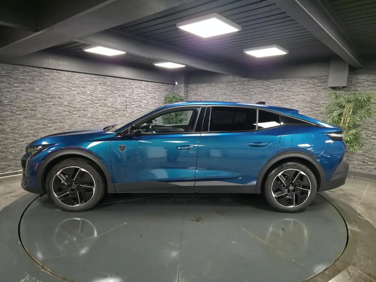 Vue de profil côté gauche d'une Peugeot 408 hybride rechargeable bleu métallisé avec jantes alliage 19 pouces dans un showroom.
