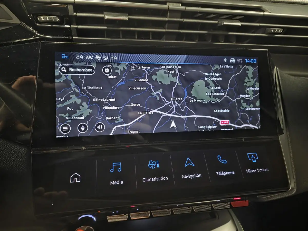 Écran tactile central du Peugeot 408 2024 affichant la navigation, entouré de la console noire brillante.