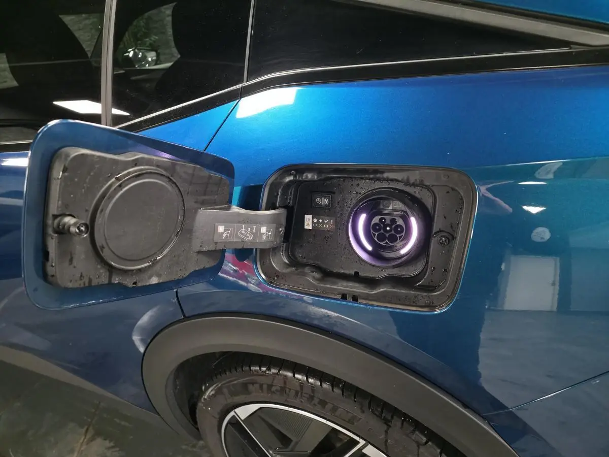 Prise de recharge ouverte côté gauche arrière d'une Peugeot 408 hybride rechargeable bleu métallisé.