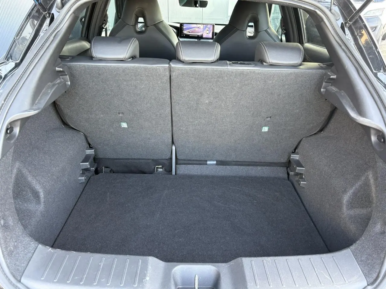 Coffre ouvert du Nissan Juke 2024 Black Pearl, vue arrière montrant l’espace de chargement et les sièges arrière rabattus.