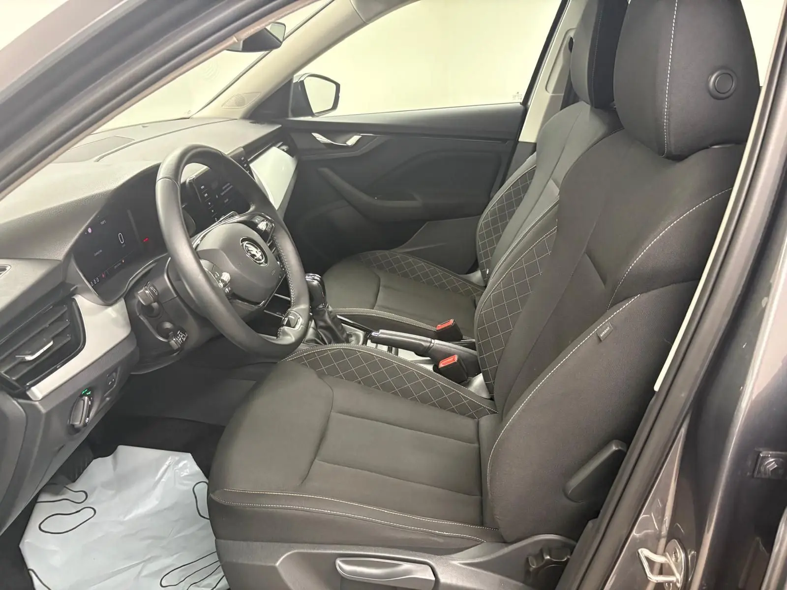 Intérieur de la SKODA KAMIQ 2023 en gris graphite, vue côté gauche sur les sièges avant et le tableau de bord moderne.