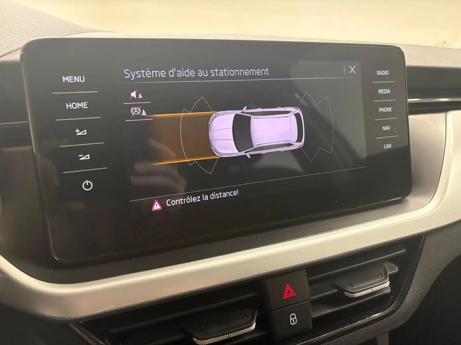 Écran central du Skoda Kamiq 2023 montrant le système d'aide au stationnement avec interface claire et boutons tactiles.