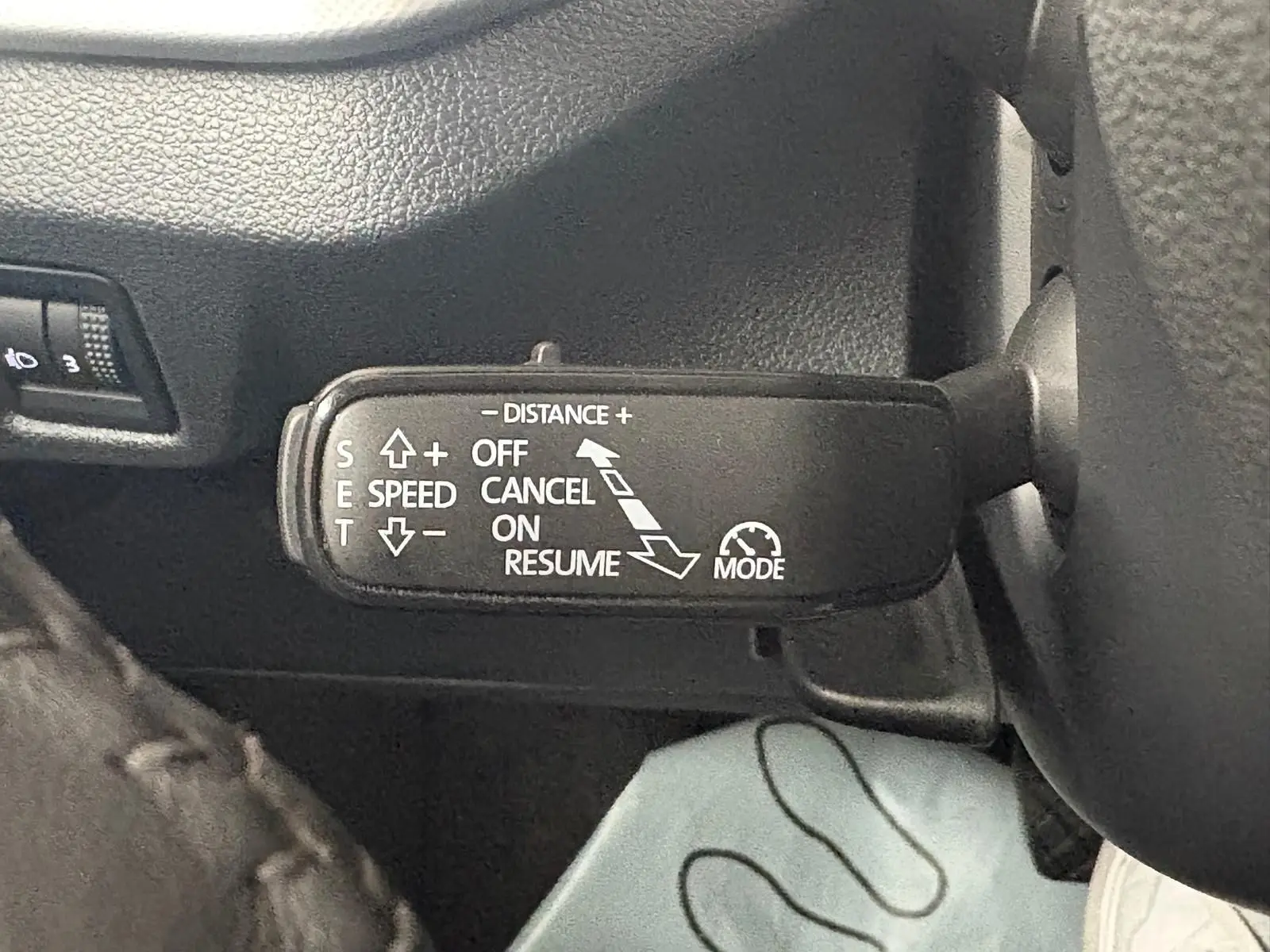 Gros plan sur la commande de régulateur de vitesse au volant d’un Skoda Kamiq gris graphite 2023.