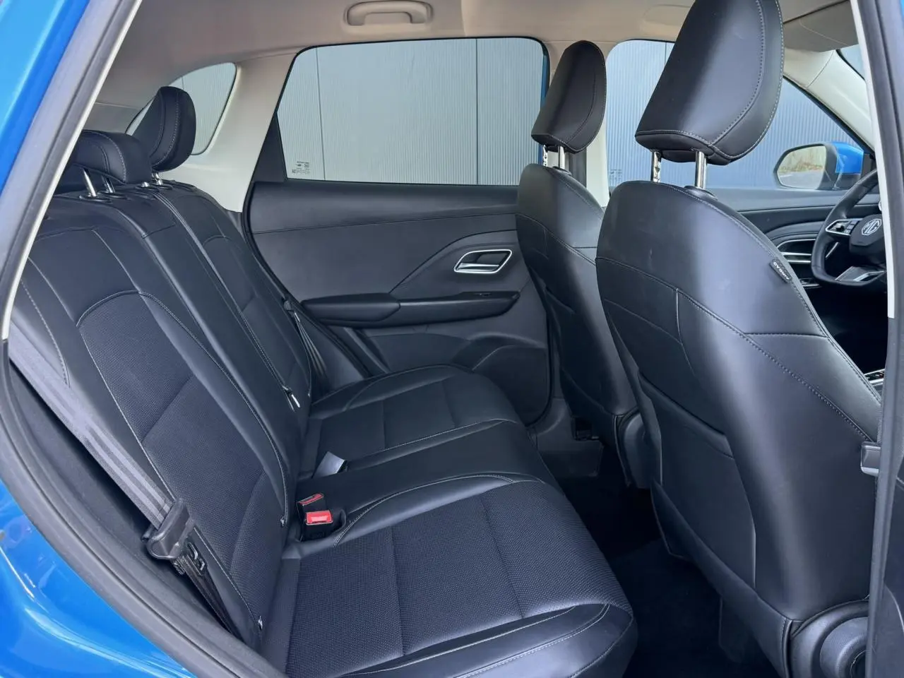 Vue intérieure côté gauche montrant la banquette arrière en similicuir noir du MG ZS 1.5 Hybrid+ 197 Luxury bleu Como.