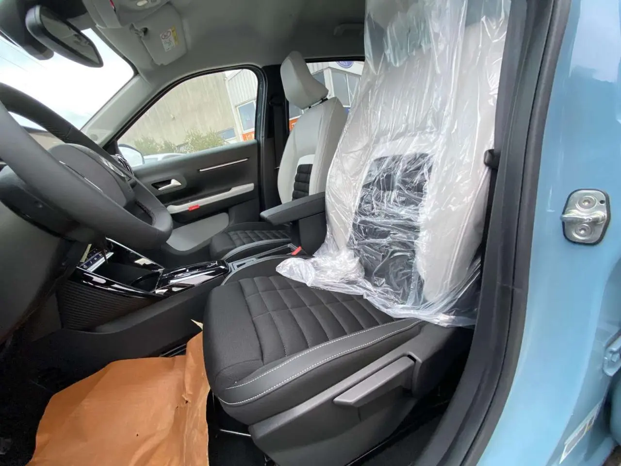 Vue intérieure côté conducteur du Citroën C3 Aircross bleu Monte Carlo, sièges noirs avec protections plastiques visibles.