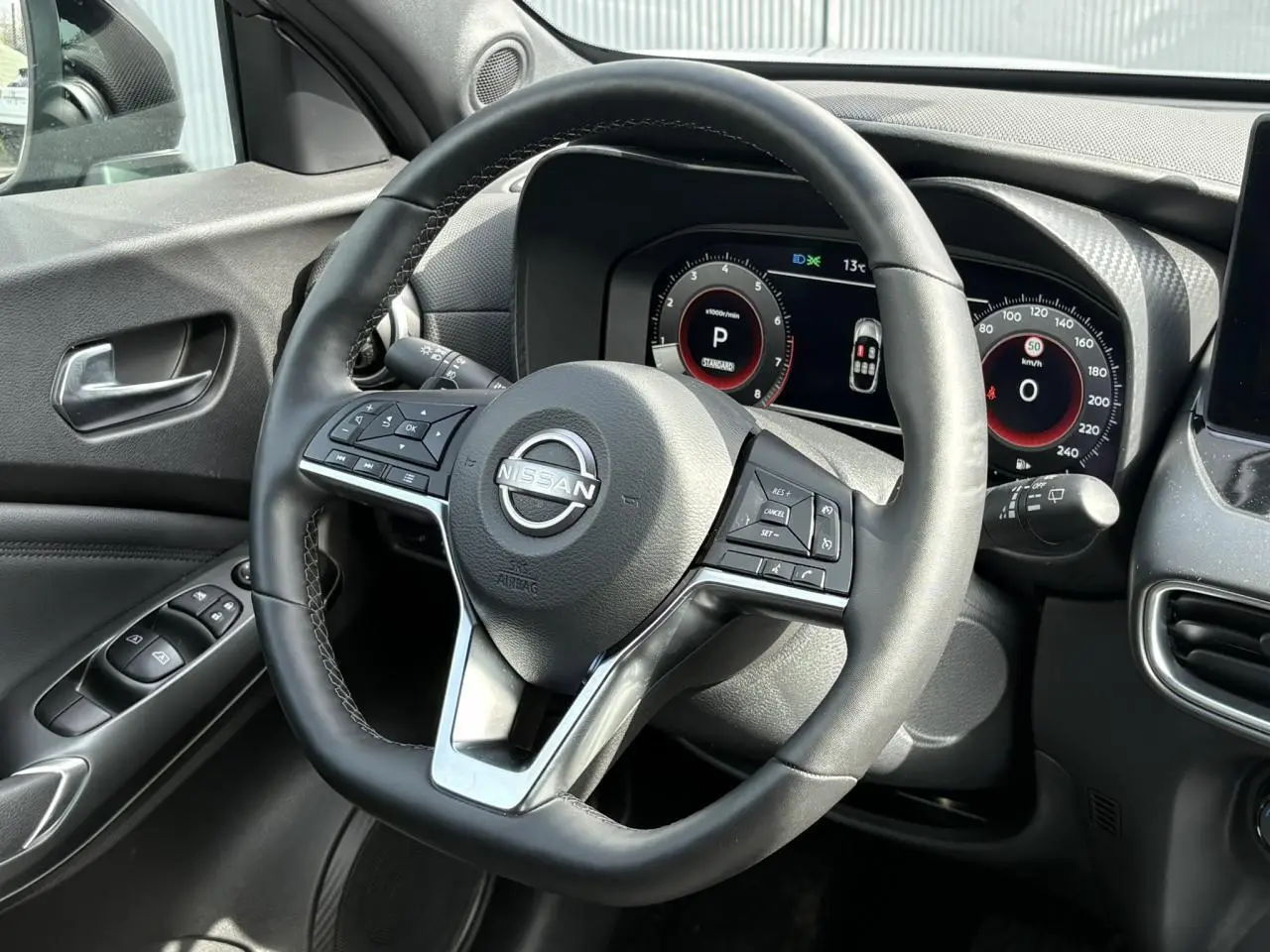 Vue rapprochée du volant noir et du tableau de bord numérique du Nissan Juke 2025 côté conducteur.
