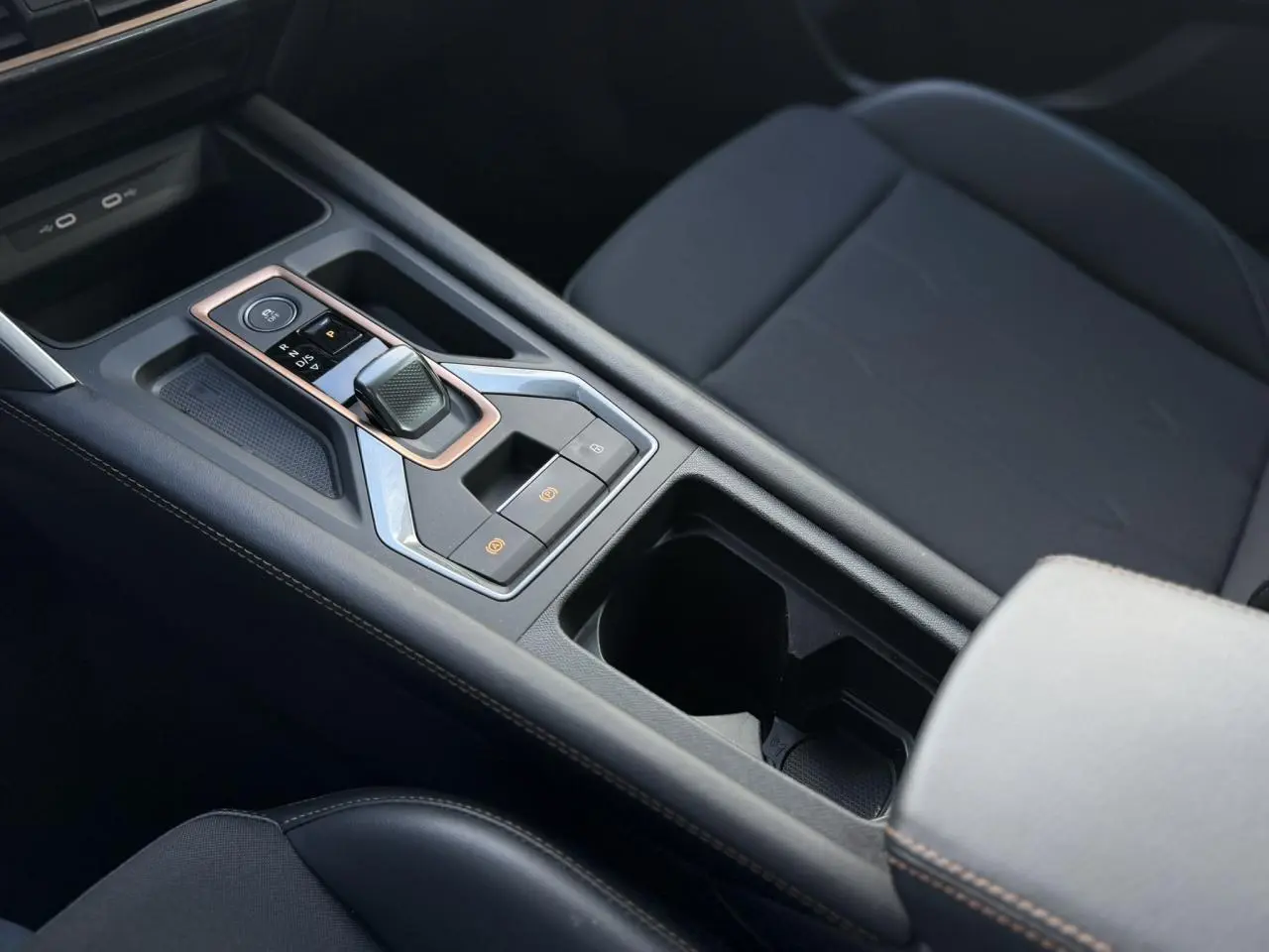 Gros plan sur la console centrale noire avec levier de vitesse automatique et accoudoir avant gris clair du CUPRA Formentor.