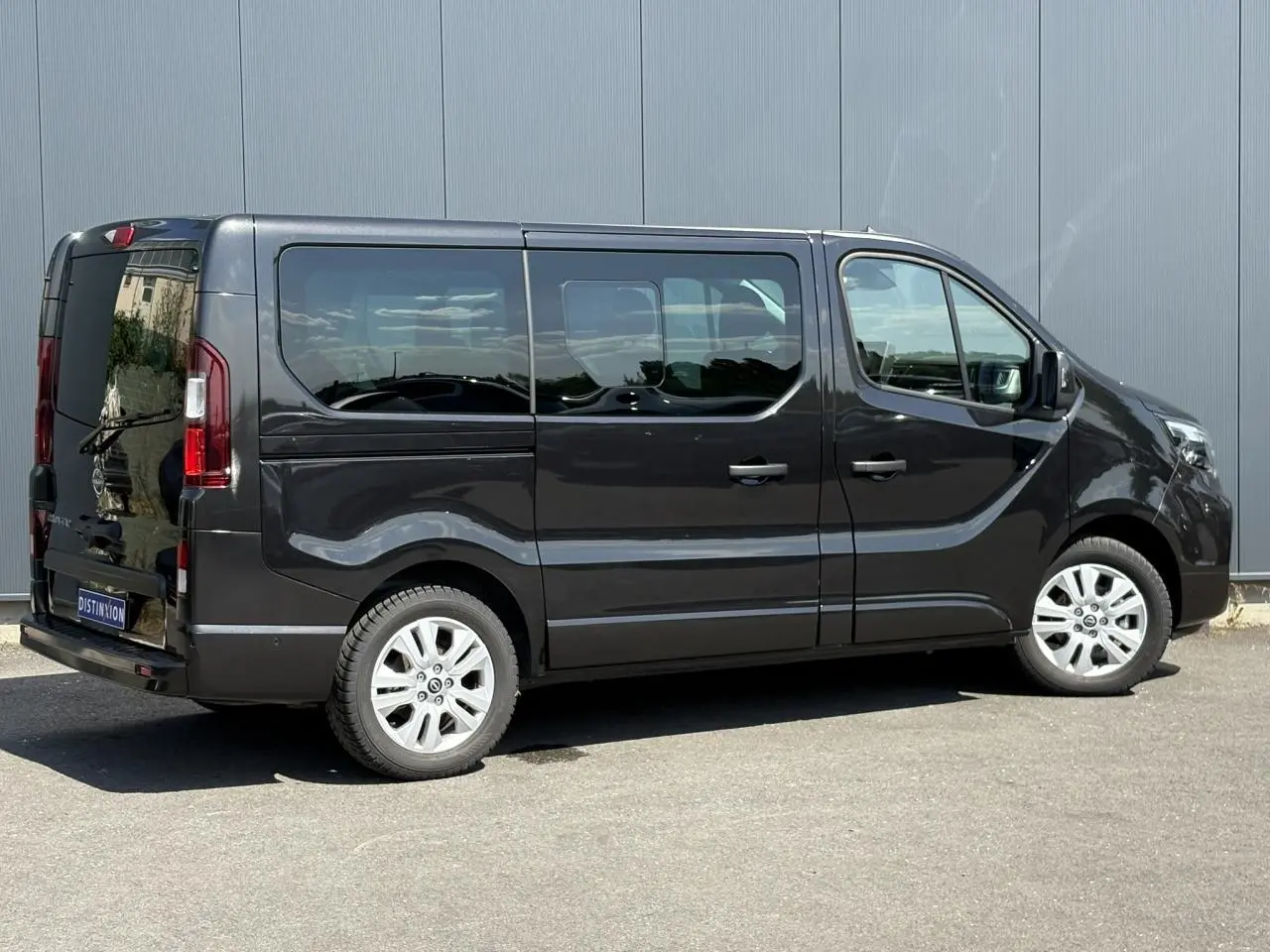 Vue latérale droite d'un Nissan Primastar Combi noir Minuit avec vitres arrière surteintées et jantes alliage 17 pouces.