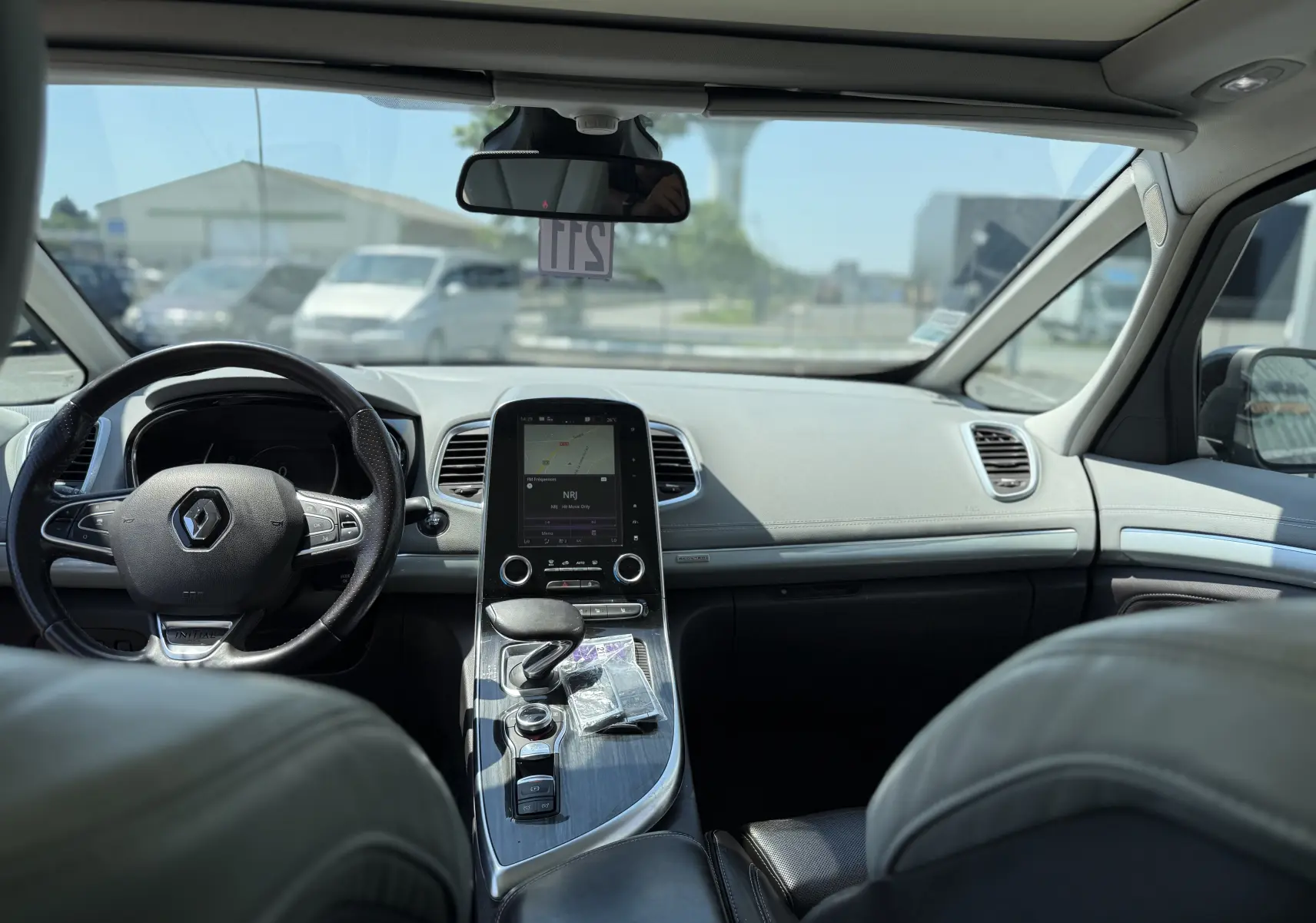 Vue intérieure avant de la Renault Espace V noire, mettant en valeur le tableau de bord moderne avec écran tactile et volant cuir.