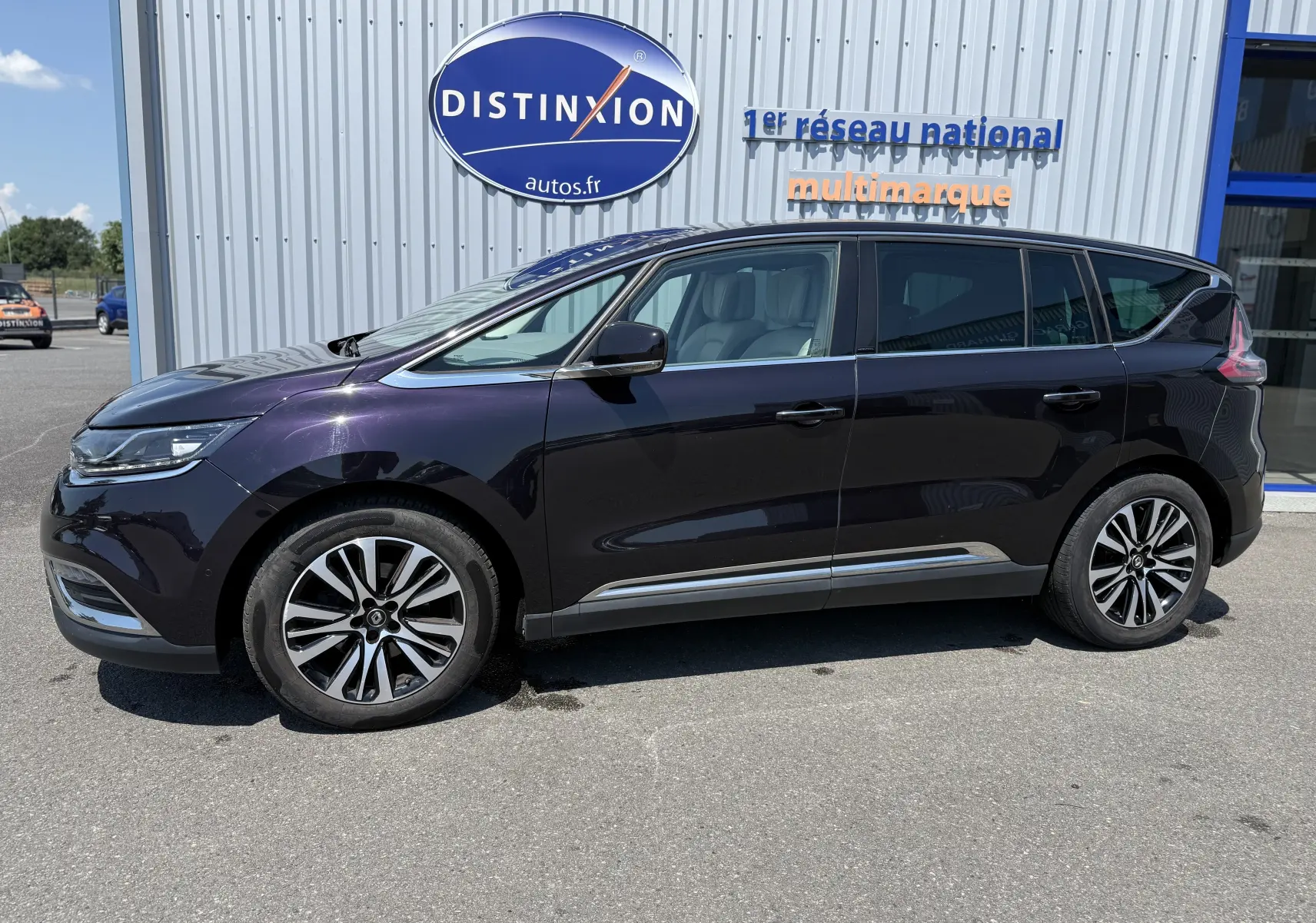 Profil côté gauche d'un Renault Espace V noir 2017, avec jantes bi-ton 19 pouces et vitres teintées, stationné devant un bâtiment.