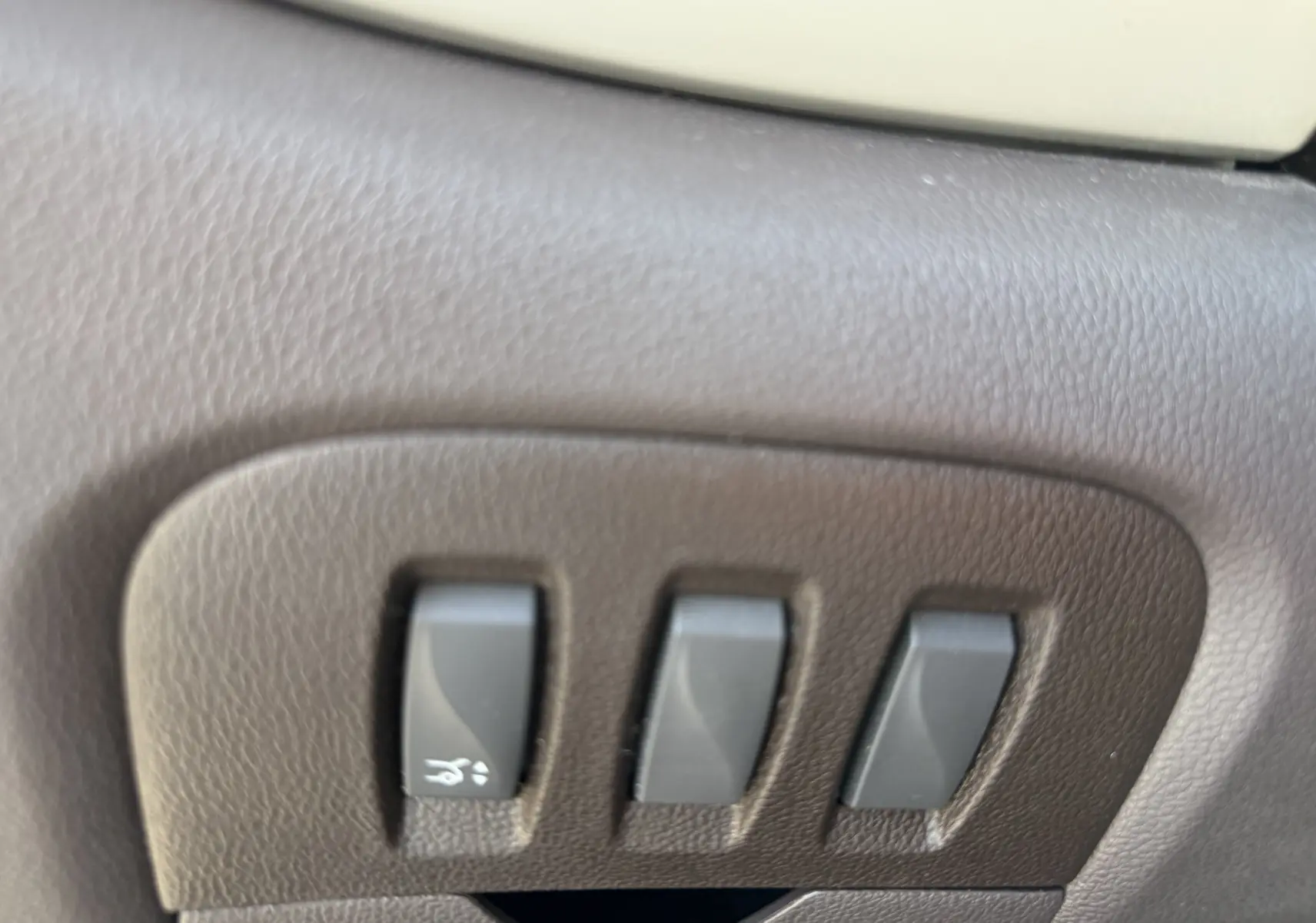 Gros plan sur les commandes de réglage électrique des sièges en cuir marron du Renault Espace V noir, côté gauche.