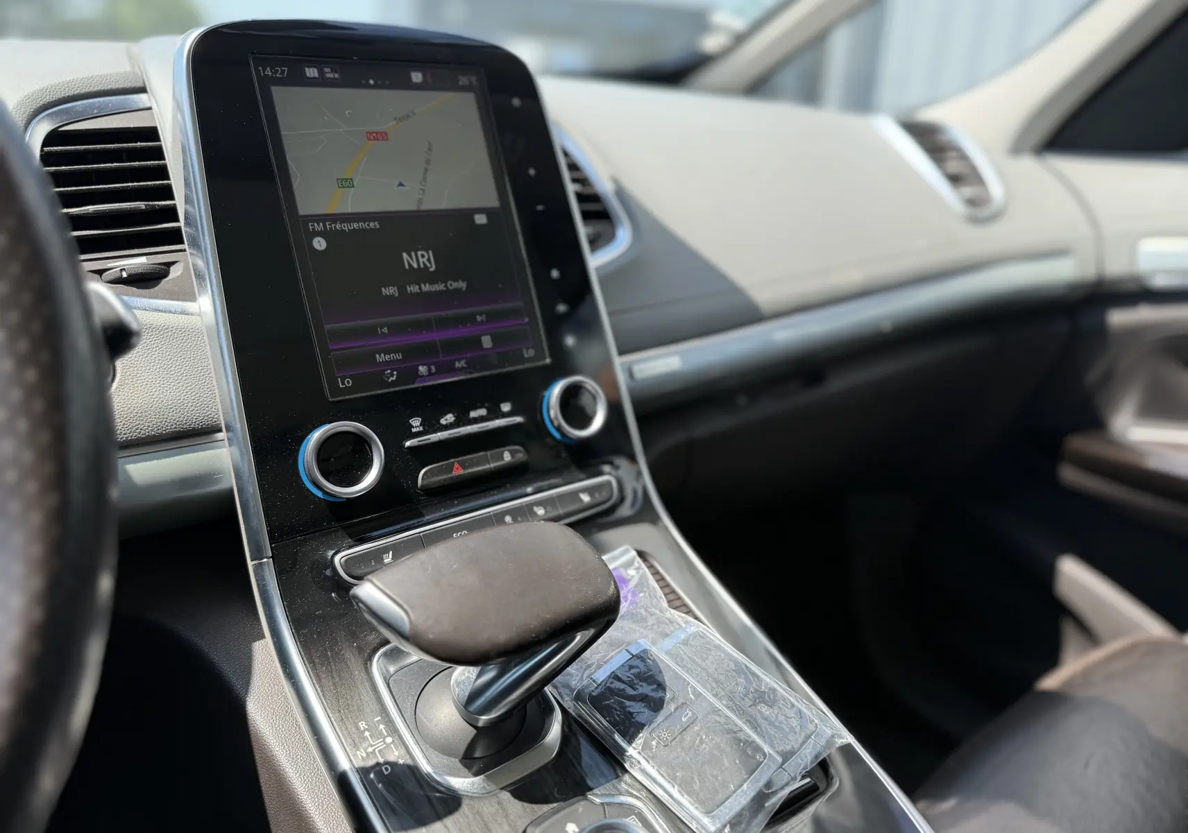 Vue intérieure centrée sur la console centrale et le levier de vitesse du Renault Espace V noir, avec écran tactile et commandes.