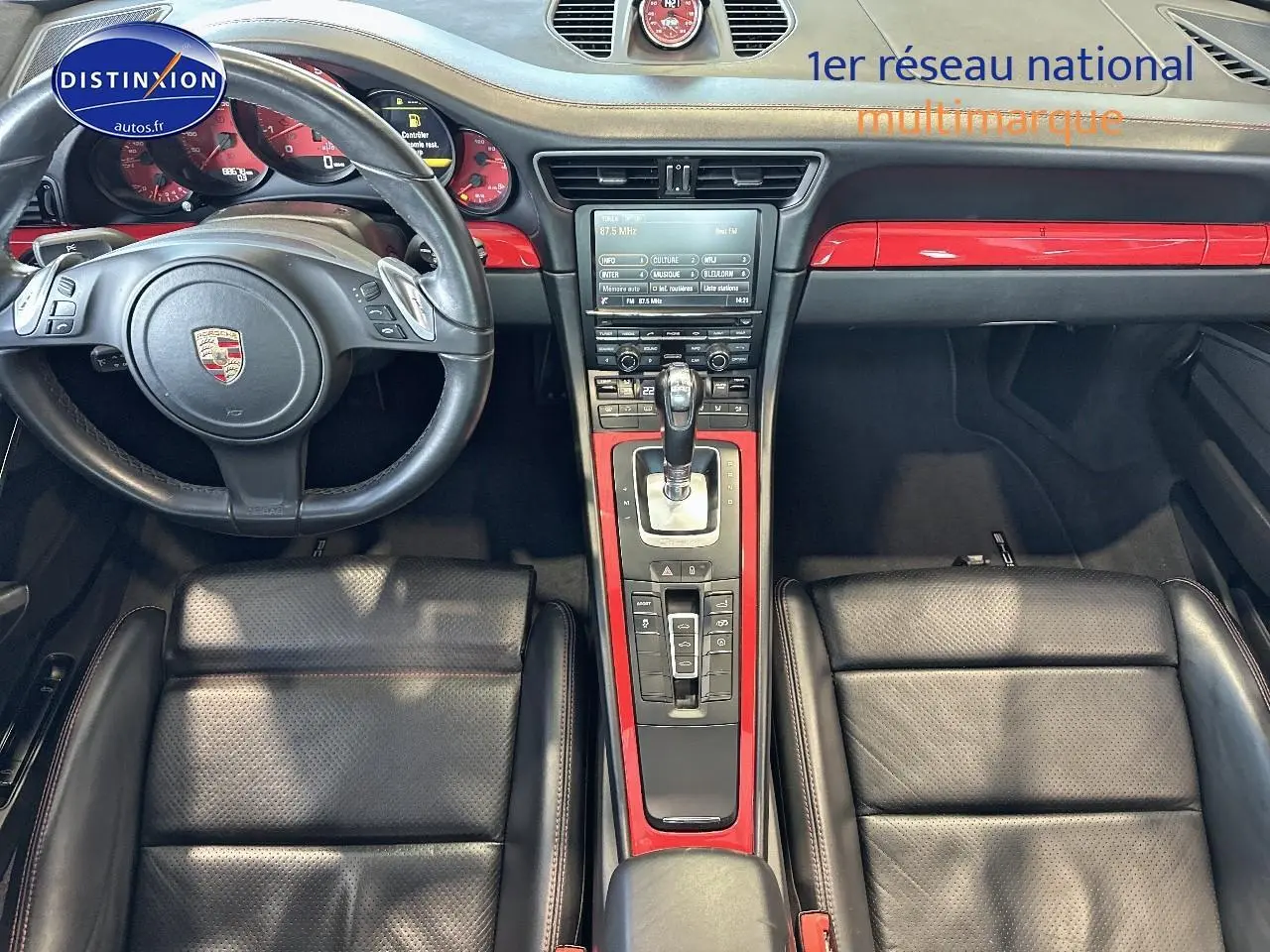 Intérieur de Porsche 911 (991) Carrera 4 PDK vu de dessus, cuir noir et inserts rouges brillants sur la console centrale.