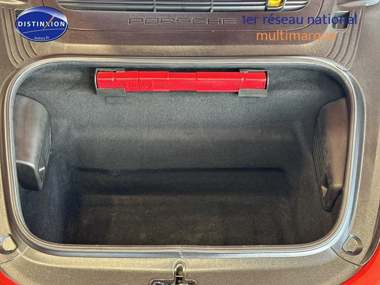 Coffre avant ouvert d'une Porsche 911 rouge (991) Carrera 4 PDK, montrant un espace de rangement vide et propre.