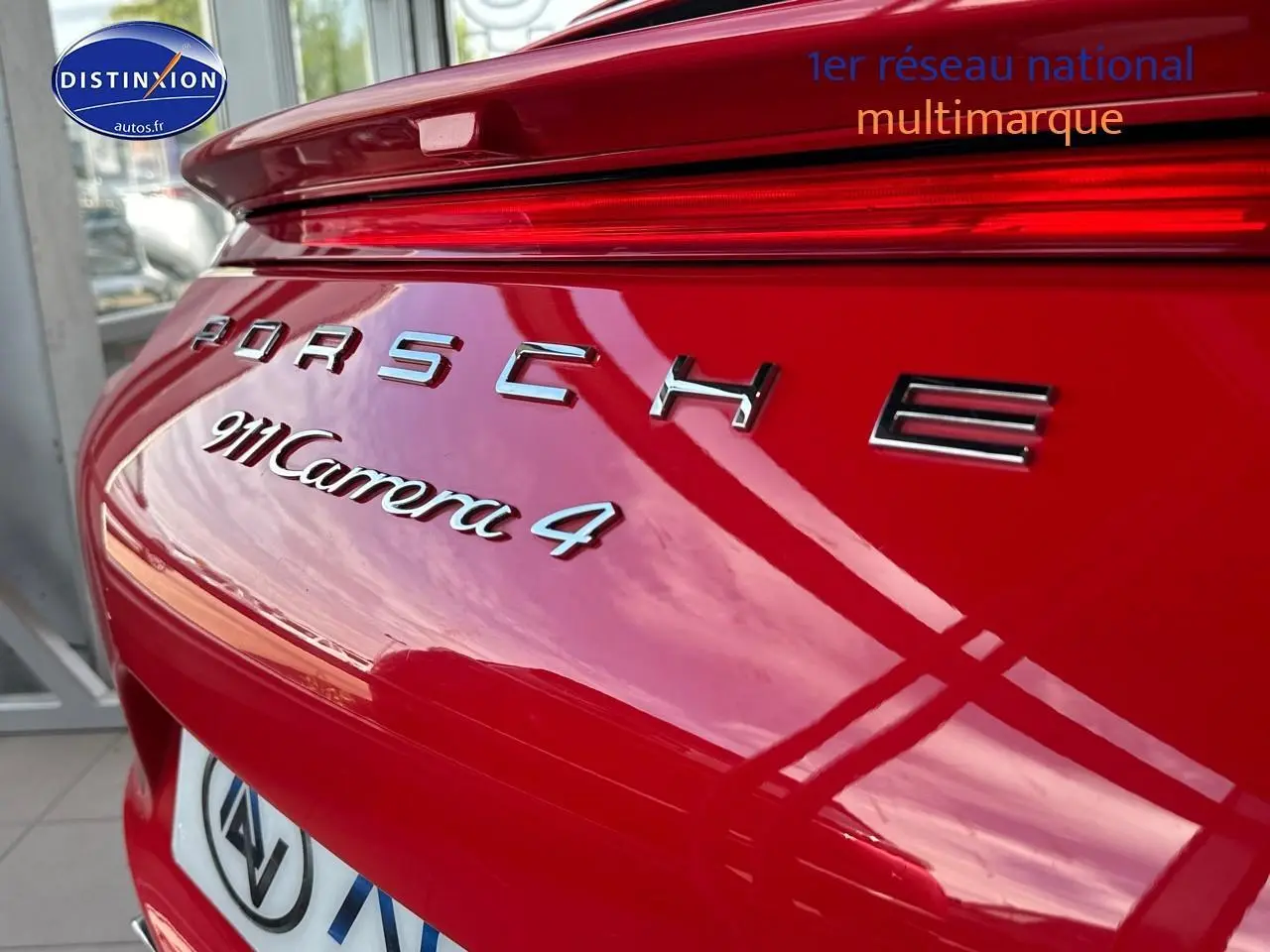 Gros plan sur l'arrière rouge brillant d'une Porsche 911 Carrera 4 avec logo et becquet intégré.