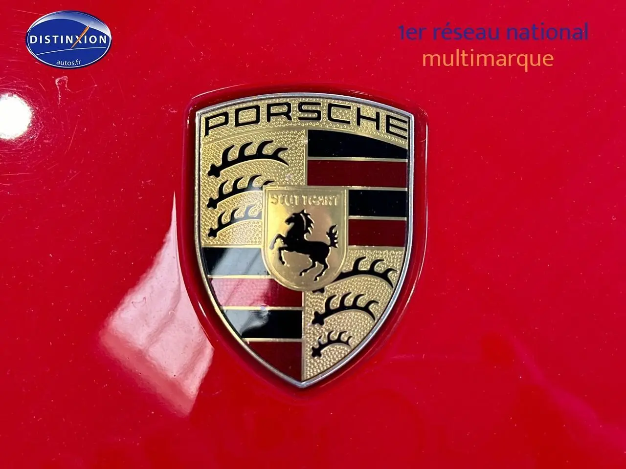 Gros plan sur l’écusson Porsche doré sur la carrosserie rouge vif d’une 911 (991) Carrera 4 PDK de 2013.