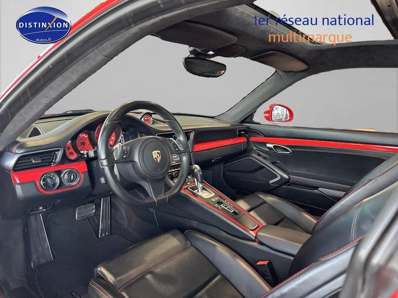 Intérieur noir et rouge de Porsche 911 (991) Carrera 4 PDK vu côté conducteur, soulignant le tableau de bord et la console centrale.